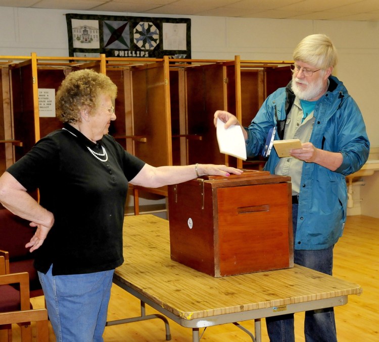 Phillips ballot clerk Lorraine Berry opens the ballot box for resident Alan Morse during SAD 58 budget voting on Tuesday. Residents of Phillips, Strong, Avon and Kingfield voted on the SAD 58 budget, which had been reduced from $9.4 million to about $260,000.