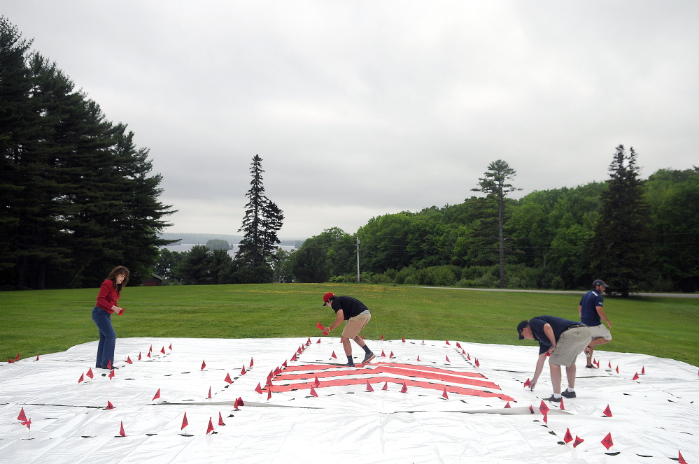 Members of the Boston Red Sox grounds crew stake out the lawn Tuesday at the Travis Mills Foundation National Family Retreat Center in Rome. The Fenway Park crew created a stencil to kick off the renovation and restoration of the retreat for combat-wounded and disabled veterans and their families.