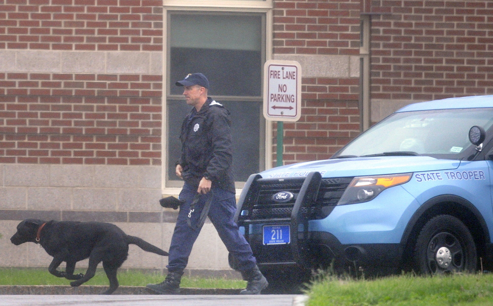 A state trooper escorts a police dog June 2 around the exterior of Cony High School in Augusta after an evacuation because of a bomb threat. Since then, two more threats have been reported.
