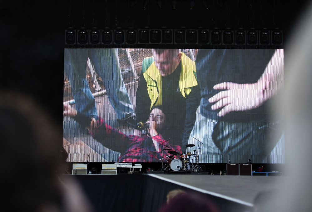 Foo Fighters’ Dave Grohl is pictured on a big screen talking in a microphone after falling from the stage, during the band’s concert at Nya Ullevi in Gothenburg, Sweden, on Friday. Grohl broke his leg in the fall.