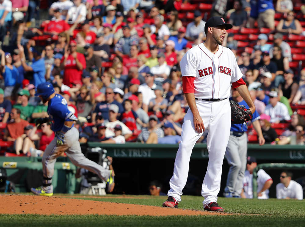 Boston Red Sox relief pitcher Matt Barnes stands on the mound after giving up the winning home run to Toronto Blue Jays’ Russell Martin, left, during the 11th inning of Toronto’s 5-4 win in a baseball game at Fenway Park in Boston Saturday.