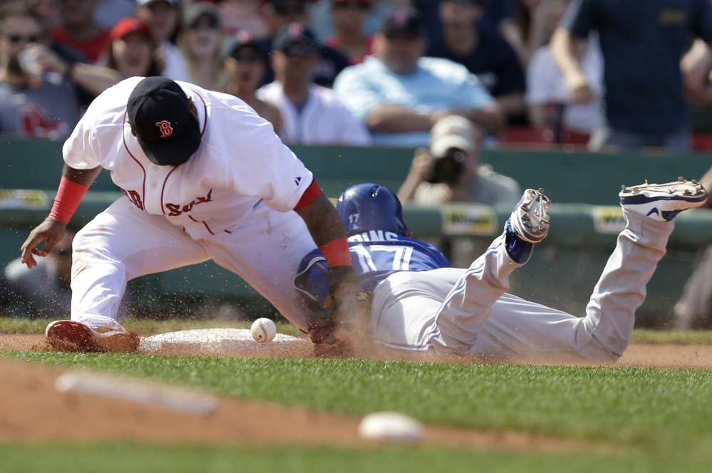 Boston’s Pablo Sandoval, left, is unable to tag Toronto’s Ryan Goins, right, as Goins advances to third base on an error in the seventh inning Sunday at Fenway Park in Boston.