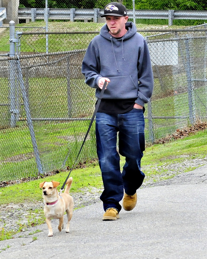 A man takes his dog for a walk past the Oakland Town Office on Cascade Mill Road Monday. The council passed an amendment to the town’s animal control ordinance requiring dog owners to clean up after their pets.