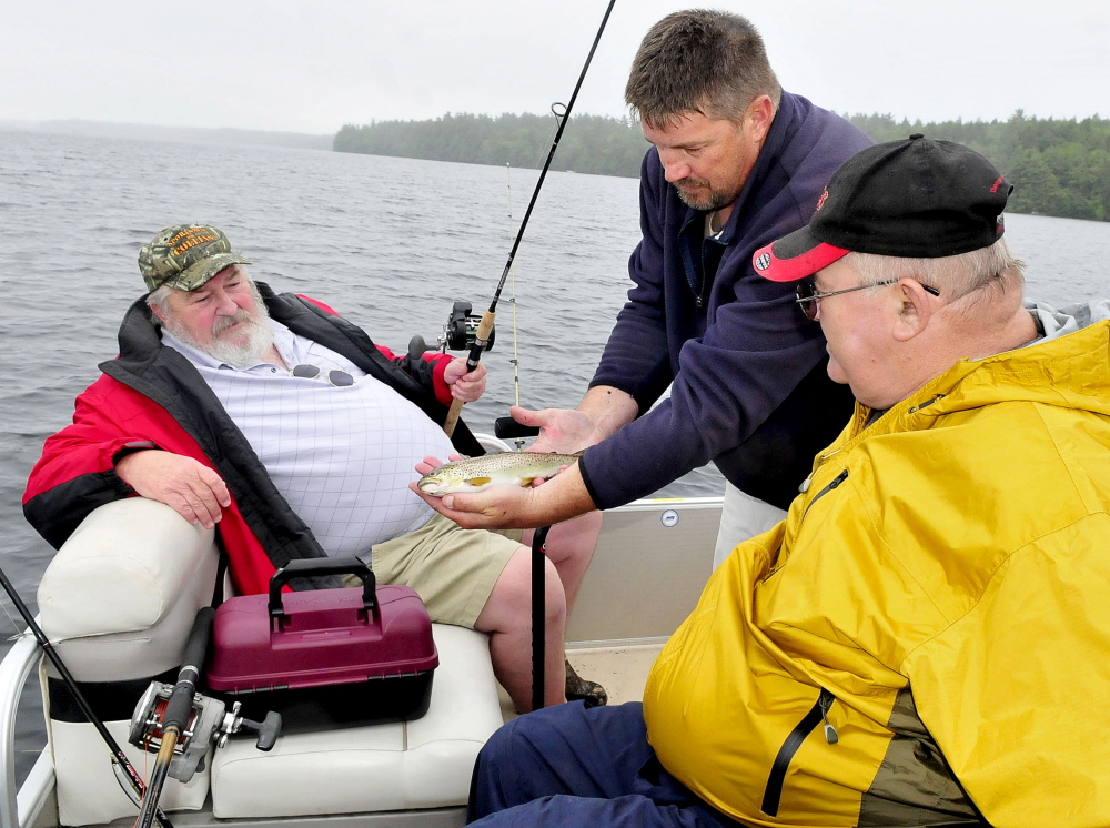 Volunteer boat captain Paul Stevens, of Belgrade, center, shows the brook trout that veteran Linwood Brayall, right, of West Gardiner, caught Tuesday on Great Pond in Belgrade. At left is veteran Carl Pettengill, of Farmingdale. The men took part in the Fishing Extravaganza, which provides an opportunity to relax and socialize with other veterans.