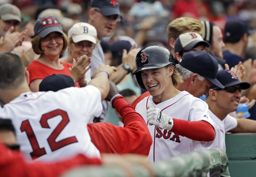 Boston Red Sox’s Brock Holt celebrates in the dugout after hitting a solo homer in the seventh inning Tuesday against the Atlanta Braves at Fenway Park in Boston. Holt hit for the cycle in Boston’s 9-4 win.