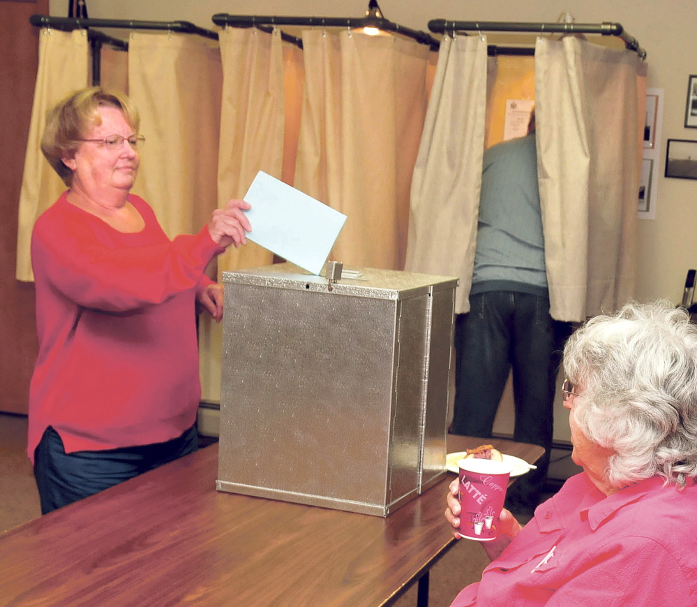 Benton resident Patricia Evers casts her School Administrative District 49 school budget ballot as her husband, Jim, fills out his and clerk Karleen Proctor monitors voting on Tuesday in Benton.