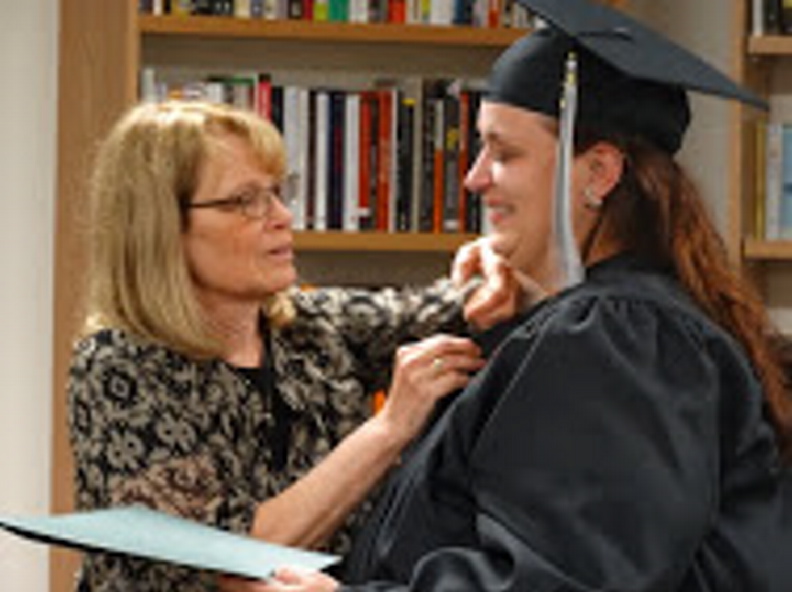From left, Christine McEwan pins Laura Jean Broski, the student graduate who received National Adult Education Honor Society induction.