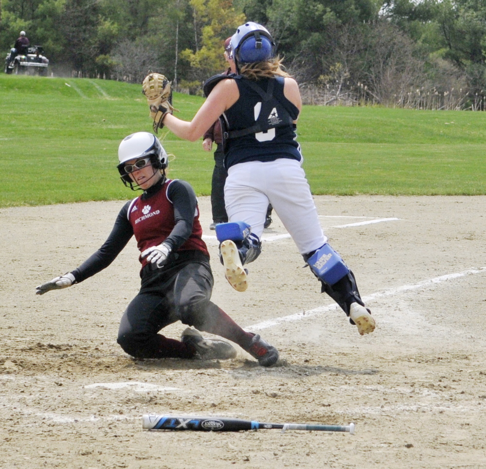 Richmond’s Sydney Tilton, bottom, slides safely into home plate by Greenville catcher Lindsay Fenn during a game May 9 in Richmond.