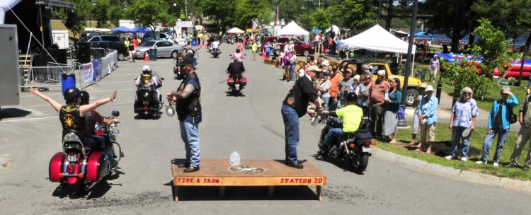 The Rev. Tony Balcer, left, and the Rev. Jack Fles sprinkle water onto passing motorcyclists Saturday at the start of a ride during the Blessing of the Bikes event, which was part of the Greater Gardiner River Festival.