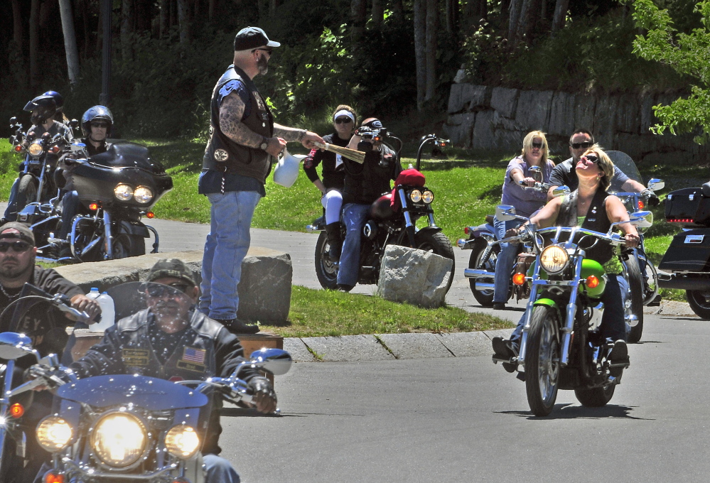 The Rev. Tony Balcer sprinkles water onto passing motorcyclists as they start a ride Saturday during the Blessing of the Bikes event, which was part of the Greater Gardiner River Festival.