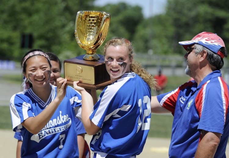 Messalonskee  team captains Mollyan Killingbeck, left, and Kristy Prelgovisk, who hit a home run in the first inning  for the only score of the game, get the trophy from their coach, Leo Bouchard after Messalonskee beat Scarborough in the Class A state championship game Saturday in Augusta.