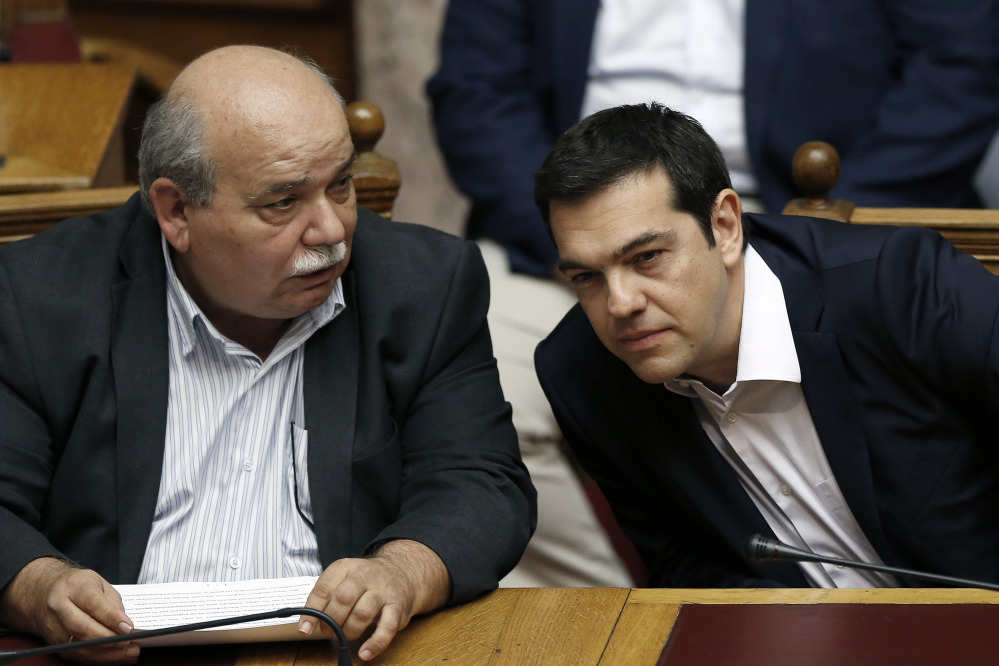 Greece’s Prime Minister Alexis Tsipras, right, chats with Greek Minister of Interior and Administrative Reconstruction Nikos Voutsis during an emergency Parliament session for the government’s proposed referendum in Athens on Saturday.
