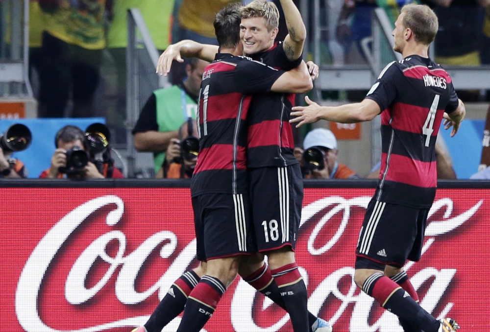 Germany’s Toni Kroos, center, celebrates near a Coca-Cola advertisement after scoring a goal during the 2014 World Cup semifinal soccer match between Brazil and Germany.