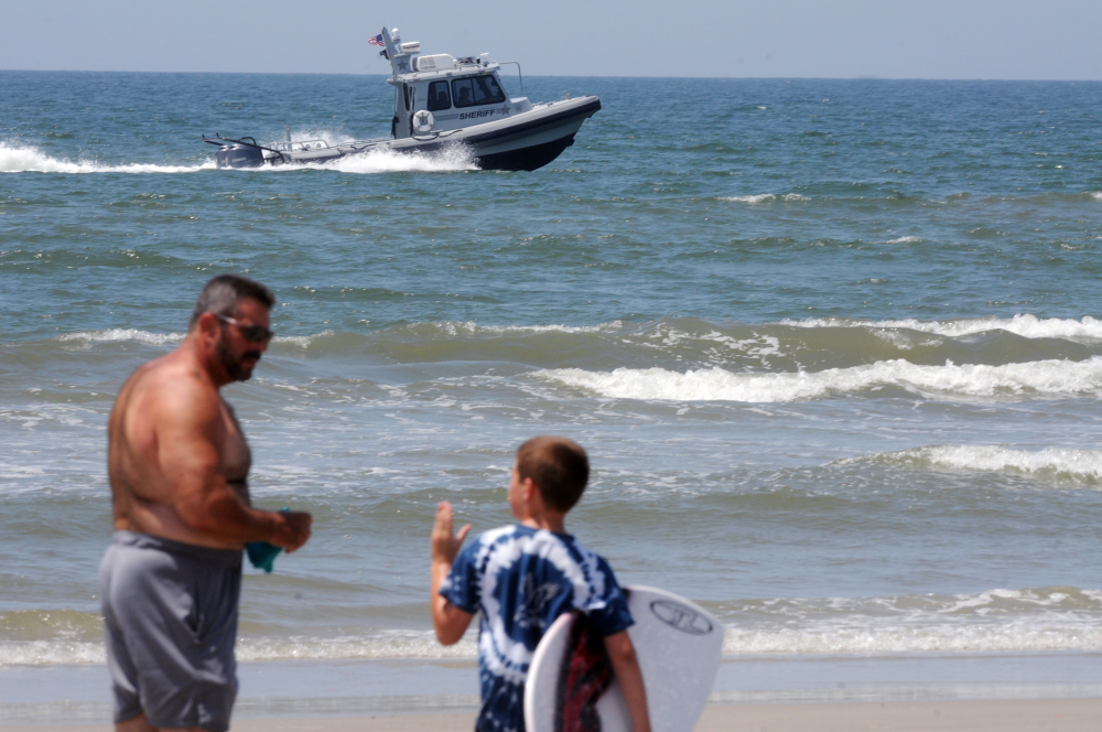 Jack Cross, 9, watches as a boat patrols the coastline near Ocean Crest Pier in Oak Island, N.C., on Monday, a day after two young people lost limbs in separate shark attacks in the town.