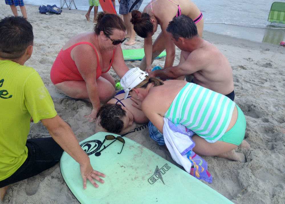 People assist a girl after she was attacked by a shark in Oak Island, N.C., on Sunday.