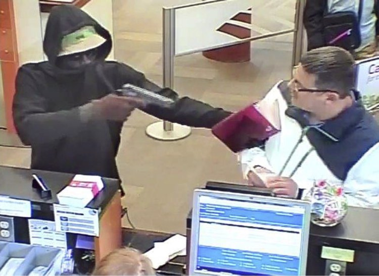 A robber points a gun at a man during the robbery of the Bank of America branch at One City Center in Portland on Friday in this image from a bank security camera.