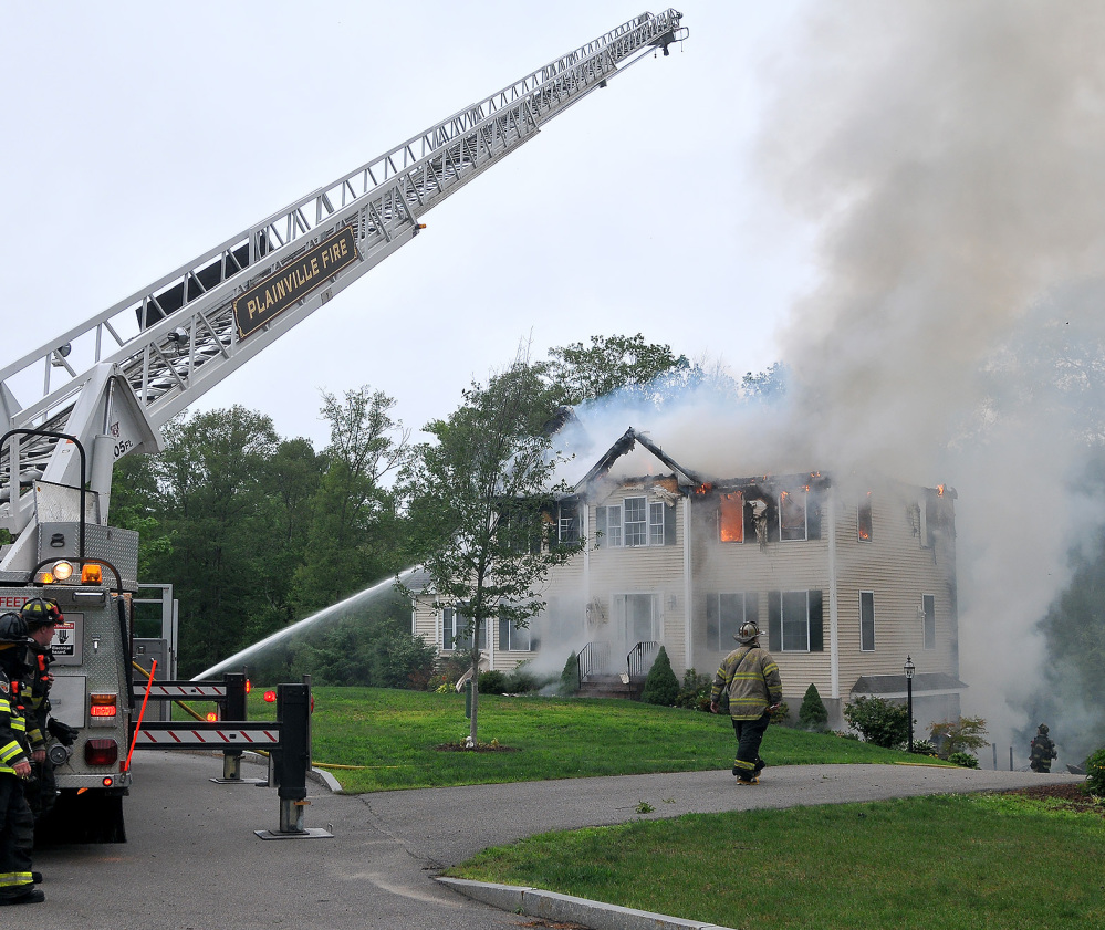 Firefighters work to extinguish flames after a small plane crashed into a house in Plainville, Mass., on Sunday.