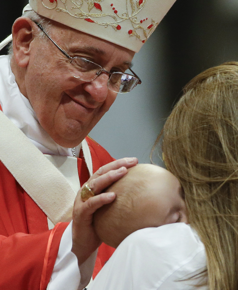 Pope Francis caresses a baby as he celebrates a mass where he bestowed the Pallium, a woolen shawl symbolizing their bond to the pope, to new Metropolitan Archbishops, in St. Peter’s Basilica at the Vatican, Monday.