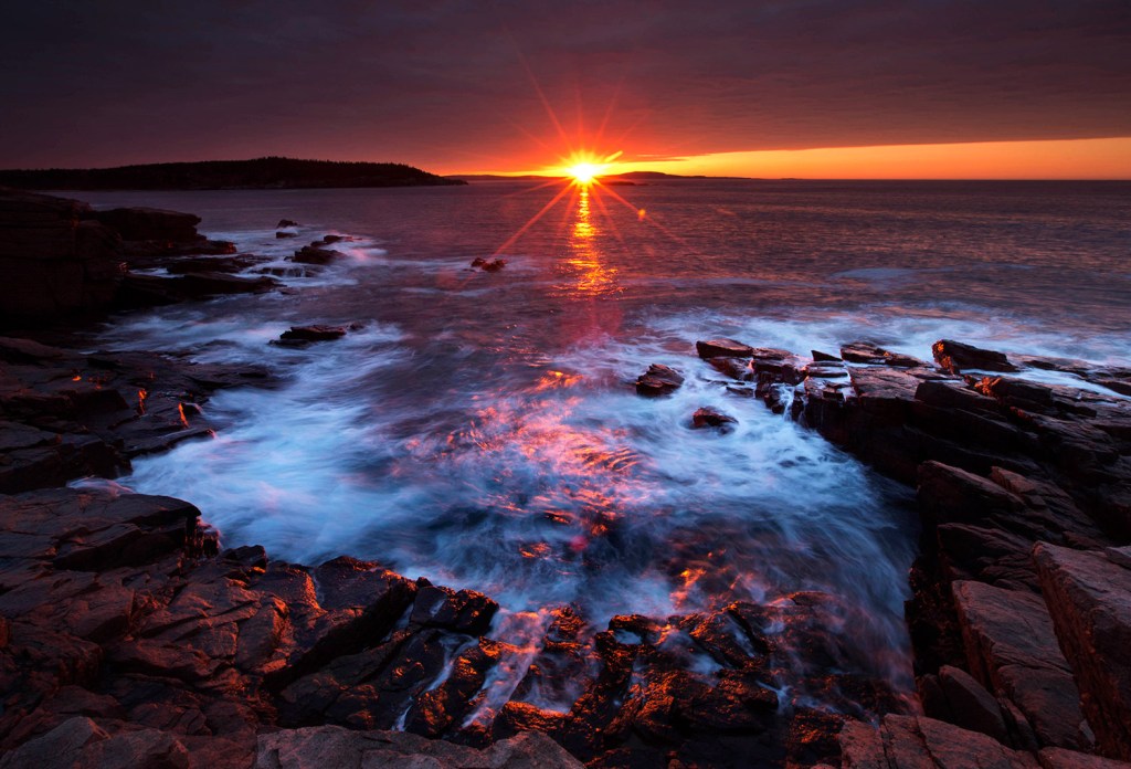 The sun's rays strike the rocky coast of Acadia National Park, Maine. The Associated Press