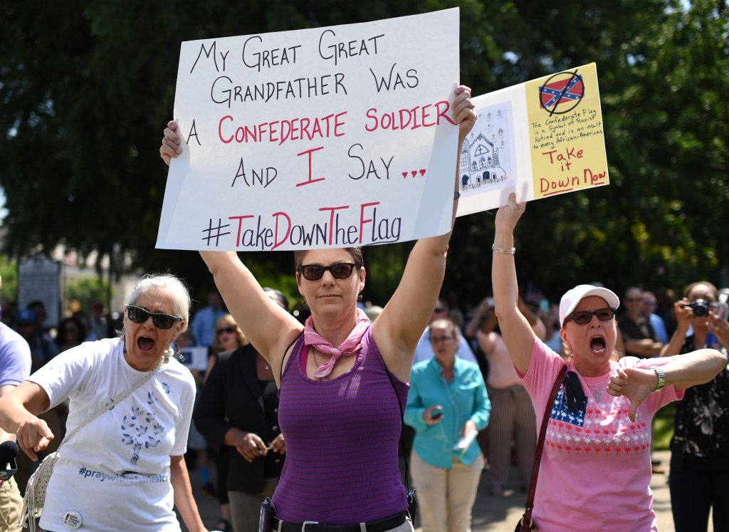 Protesters hold signs as they chant during a rally to take down the Confederate flag at the South Carolina Statehouse, Tuesday, June 23, in Columbia, S.C. Rallies are being held, and politicians have joined the chorus of voices calling for its removal, an opinion that has carried political risks in the state in the past. 