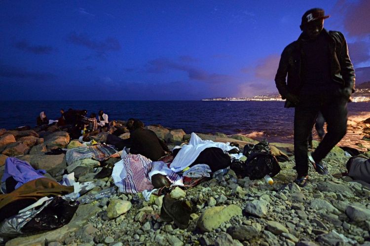 Migrants sleep on the rocks by the sea in Ventimiglia, at the border between Italy and France, early Monday. The Associated Press