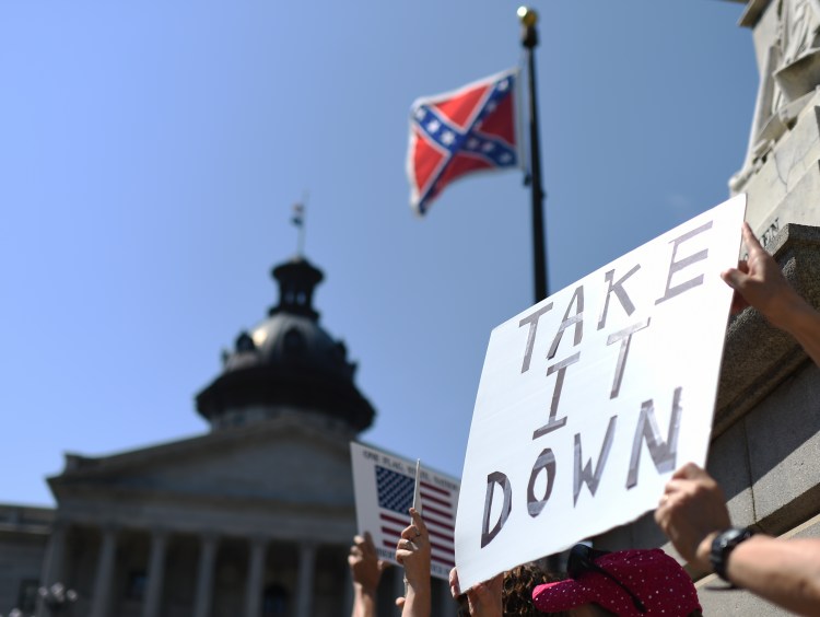 Protesters hold a sign during a rally to take down the Confederate flag at the South Carolina Statehouse, Tuesday, June 23, in Columbia, S.C. The shooting deaths of nine people at a black church in Charleston, S.C., have reignited calls for the Confederate flag flying on the grounds of the Statehouse in Columbia to come down.