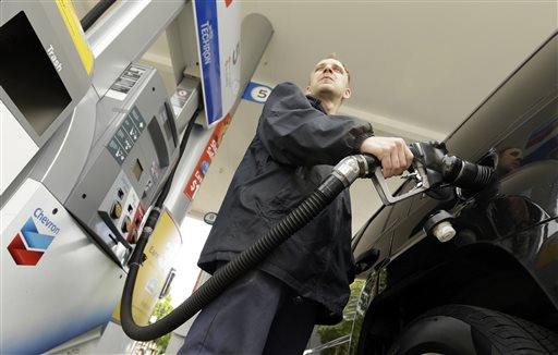 Attendant James Lewis pumps gas at a station in Portland, Ore. Even after the typical springtime run-up, the average price for gallon of regular gasoline should top out around $2.60, experts say. The Associated Press