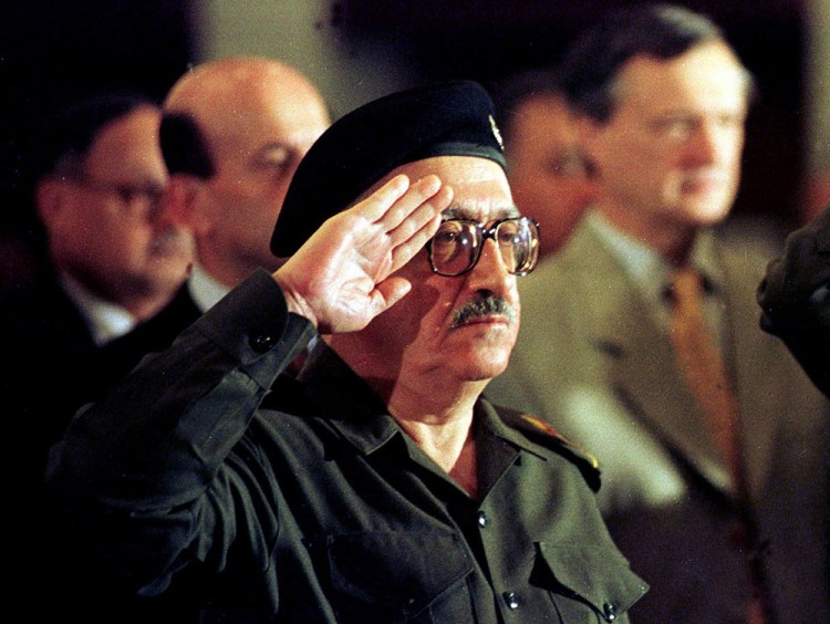 Then-Iraqi foreign minister Tariq Aziz stands at attention as the Iraqi national anthem is played at a conference in Baghdad in this 1998 photo, The Associated Press