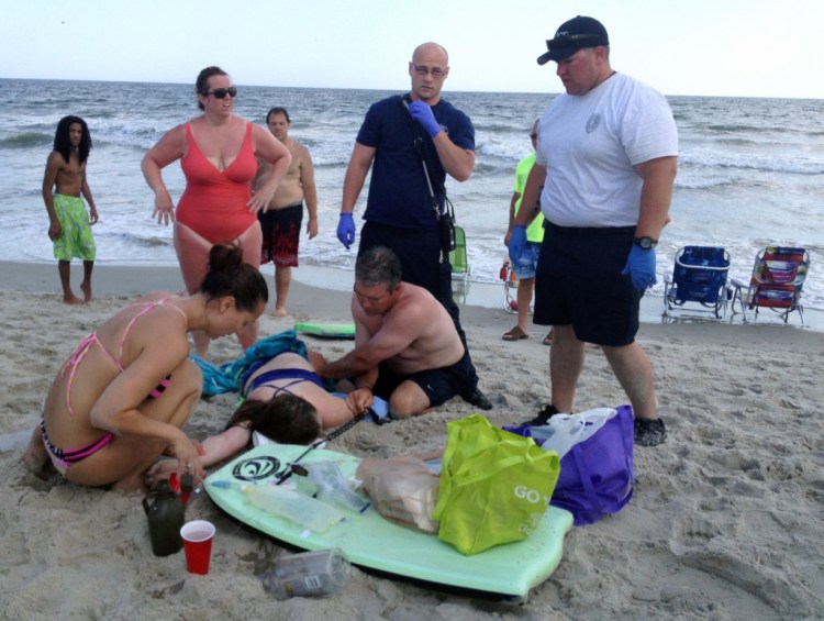 People assist a teenage girl at the scene of a shark attack in Oak Island, N.C., Sunday, June 14, 2015. Mayor Betty Wallace of Oak Island, a seaside town bordered to the south by the Atlantic Ocean, said that hours after the teenage girl suffered severe injuries in a shark attack Sunday a teenage boy was also severely injured. 