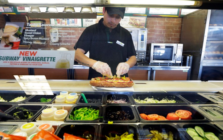 Roberto Castelan makes a sandwich at a Subway sandwich franchise in Seattle. The sandwich chain known for its marketing itself as a fresher alternative to hamburger chains said on Thursday it will remove artificial flavors, colors and preservatives from its menu in North America by 2017.