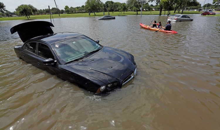 A boat paddles down a flooded street in Houston in this May 26, 2015, photo. A NOAA climate scientist calculates that cmore than 200 trillion gallons of water fell on the contiguous U.S. in May. The Associated Press