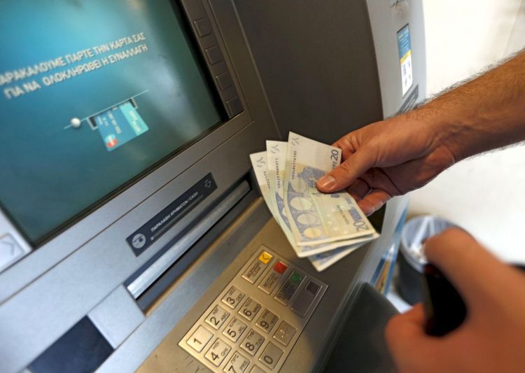A man withdraws 60 euros, the maximum amount allowed after the imposed capital controls in Greek banks, at a National Bank of Greece ATM in Piraeus port near Athens Tuesday. The head of the European Commission made a last-minute offer to try to persuade Greek Prime Minister Alexis Tsipras to accept a bailout deal he has rejected before a referendum on Sunday that EU partners say will be a choice of whether to stay in the euro. Reuters
