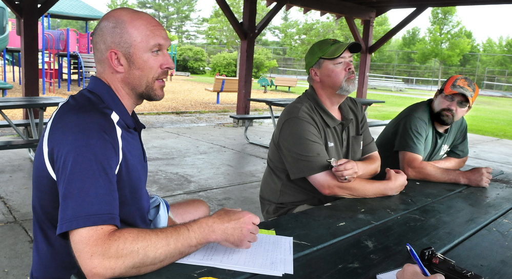 Waterville Parks and Recreation Director Matt Skehan, left, and employees Steve Buzzell and Sam Green discuss the department’s carry-in-and-carry-out policy at city parks, including the North Street park in Waterville on Wednesday. There are no longer any trash cans at the park. Those who use the park are expected to remove their own trash.