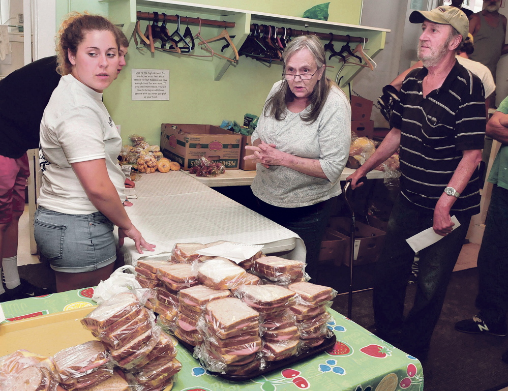 Volunteer Meg Nadeau, a member of the Winslow High School Honor Society, assists Linda Provencher and John Roy with food they selected at the Evening Sandwich Program held daily at the Universalist Unitarian Church in Waterville recently.