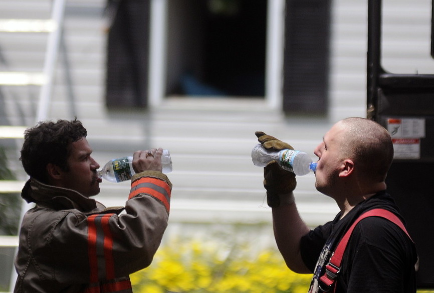 Litchfield firefighter Zakk McKinney, right, and Captain Michael Sherman cool off Sunday after helping extinguish a blaze inside a home off Route 126 in Litchfield.