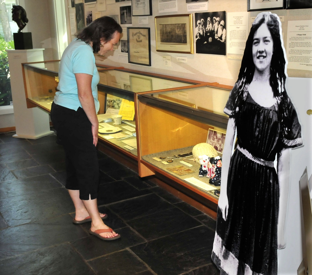Gigi Hynd looks over some of the memorabilia of the late Sen. Margaret Chase Smith, including a large photograph of her in a bathing suit, at the Smith library Skowhegan.