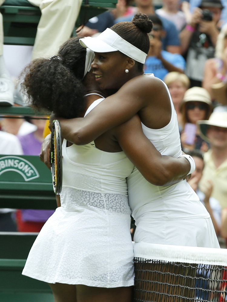 Serena Williams, left, hugs her sister Venus Williams after winning their singles match at the All England Lawn Tennis Championships on Monday in Wimbledon. Serena Williams won 6-4, 6-3.
