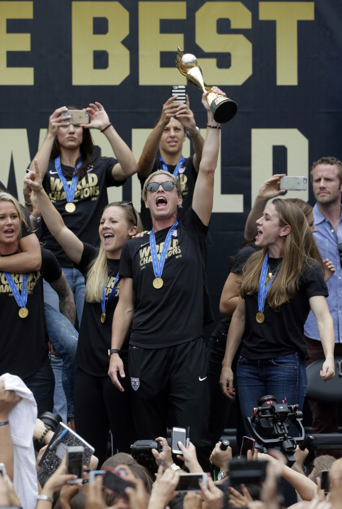 U.S. women’s soccer team forward Abby Wambach, center, hoists the trophy while celebrating the team’s World Cup championship during a public rally Tuesday in Los Angeles. This was the first U.S. stop for the team since beating Japan in the Women’s World Cup final Sunday in Canada.