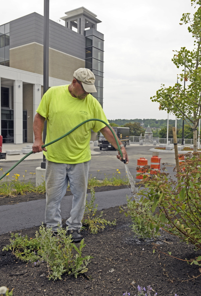 Bruce Battersby, of Salmon Falls Nursery and Landscaping in Berwick, waters new plants Thursday at the Capital Judicial Center in Augusta.
