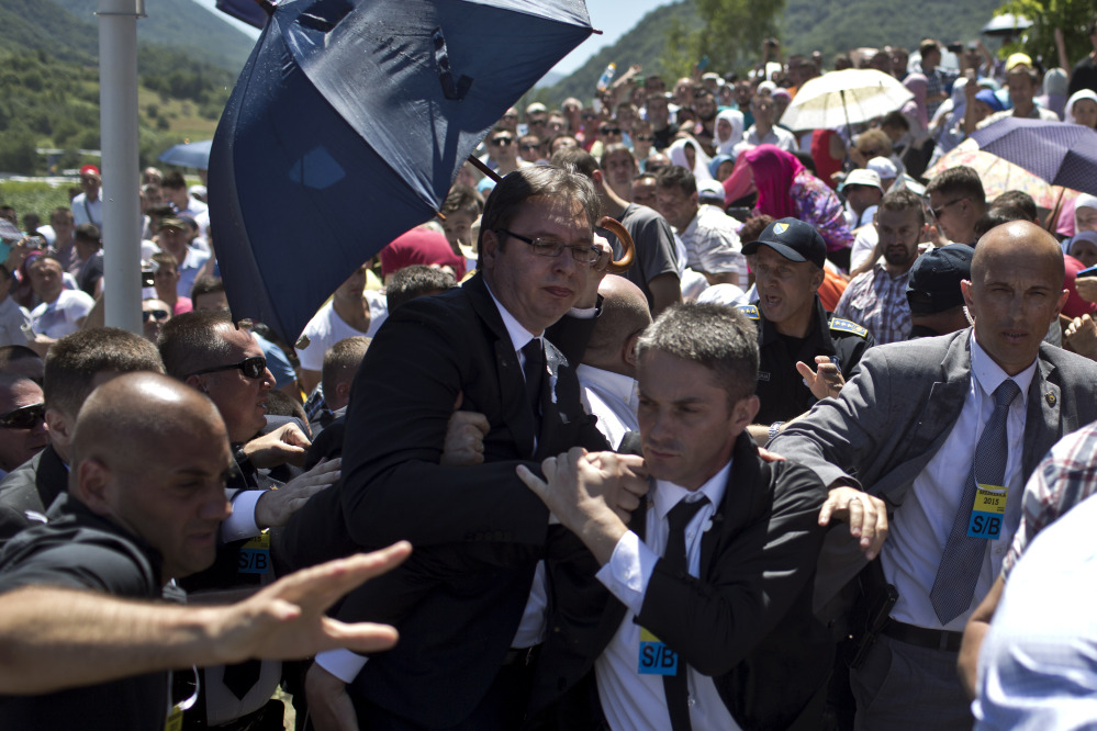 Aleksandar Vucic, Serbia’s prime minister, center, is seen during a scuffle at the Potocari memorial complex near Srebrenicaon Saturday. Anger boiled over at a massive commemoration of the Srebrenica slaughter 20 years ago as people pelted Vucic with water bottles and other objects.