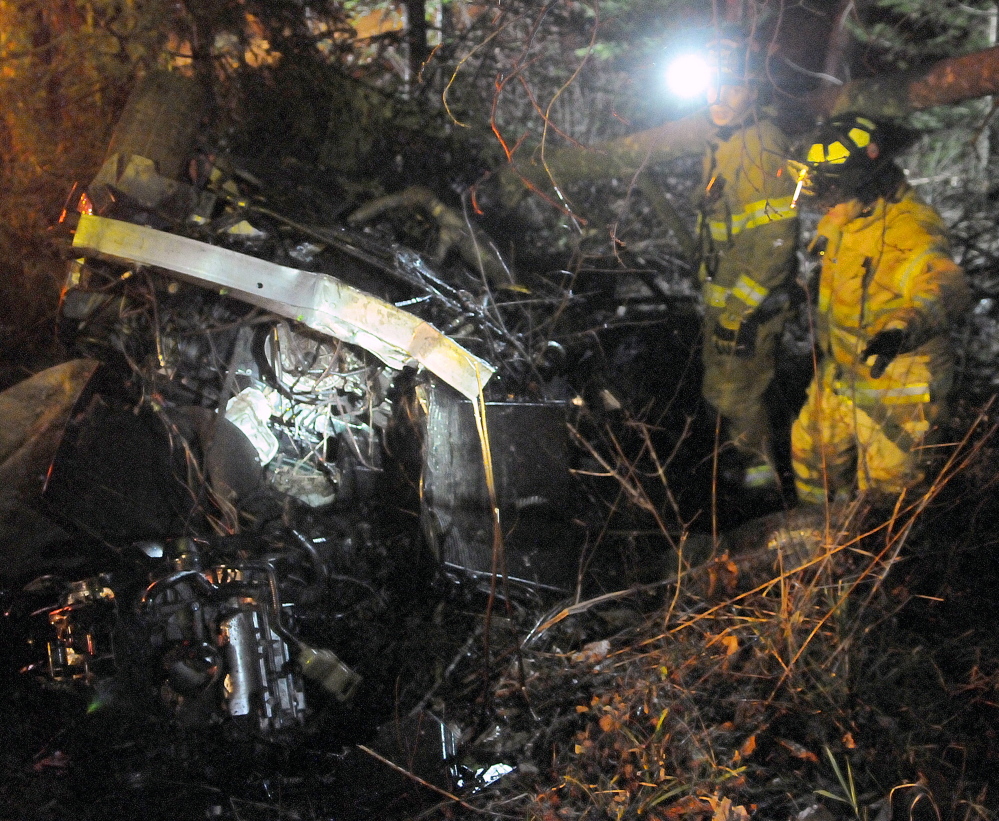 Firefighters search a vehicle Nov. 5, 2014 that rolled over on the Plains Road in Readfield, killing a passenger.