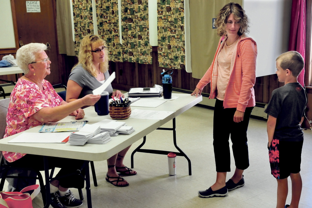 Kingfield ballot clerk Pat Meldrum, left, and Leanna Targett speak with voter Alison Royall and her son Tate before Royall voted on Thursday on whether the town should proceed with withdrawing from Regional School Unit 58.