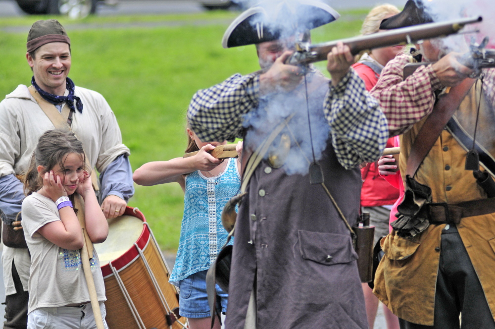 Emily Day, 9, of Auburn, left, cover her ears as re-enactors fire a volley Saturday during an Old Fort Western encampment set up for the annual Old Hallowell Day celebration in Hallowell. Peter Morrissey, as Capt. James Howard, right, led children in marching drills with firing around a field beside Hallowell Seafood.