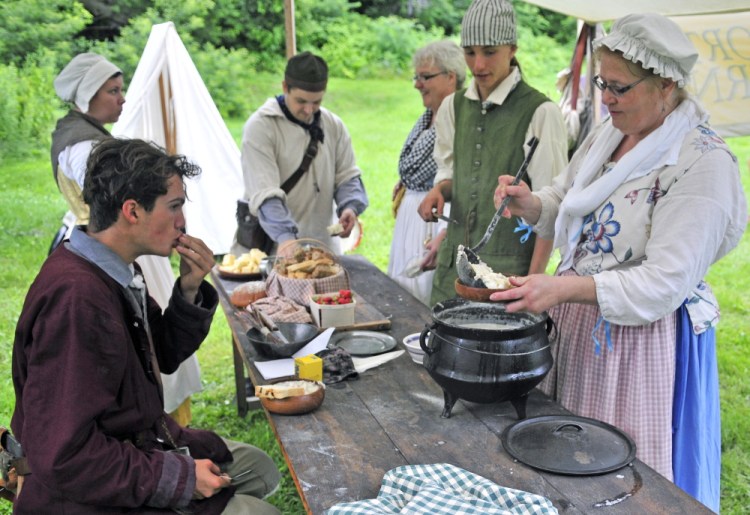 Old Fort Western director Linda Novak serves fish chowder that she cooked over an open fire to other re-enactors during an encampment Saturday as part of the Old Hallowell Day celebration in Hallowell.