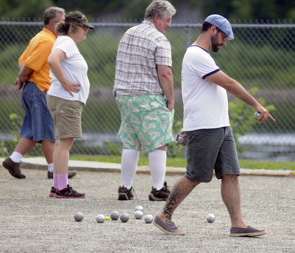 Stephen Lessard points to a throw of a petanque ball Sunday during an annual tournament in Mill Park in Augusta.