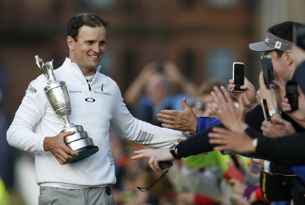 AP photo 
 Zach Johnson celebrates with members of the public as he holds the trophy after winning a playoff after the final round at the British Open on Monday.