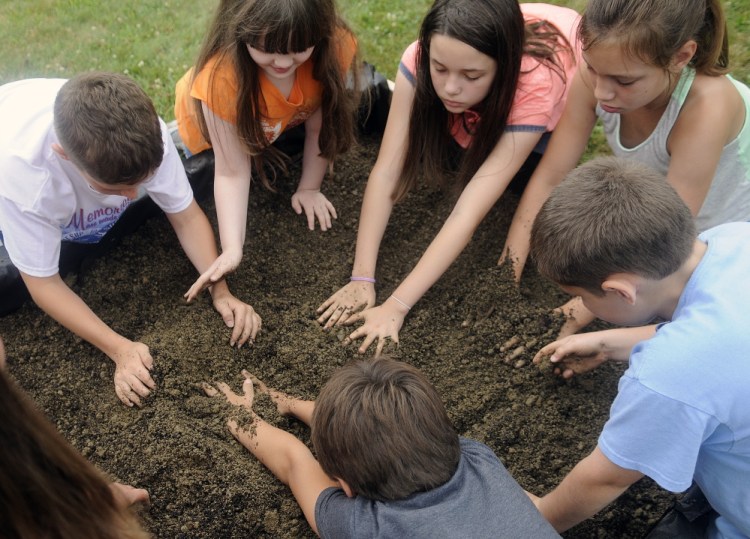 Children mix compost and soil together Monday in the new garden beds erected at the Buker Community Center in Augusta.