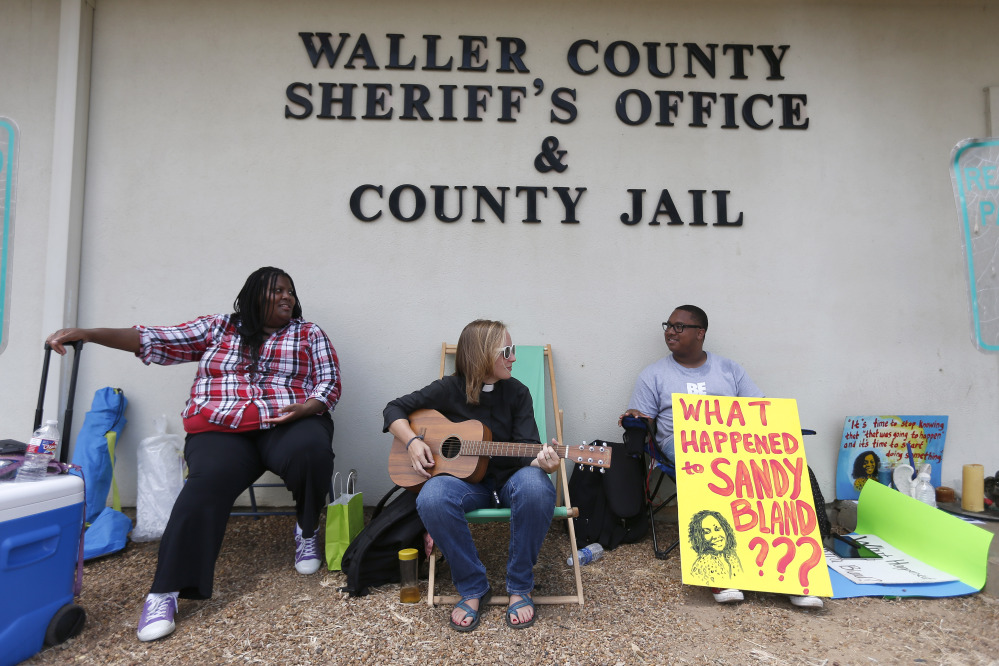 Carie Cauley, left, Rev. Hannah Bonner and Rhys Caraway protest, after the death of Sandra Bland, as they sit in front of the Waller County Sheriff’s Office and county jail on Monday, in Hempstead, Texas.