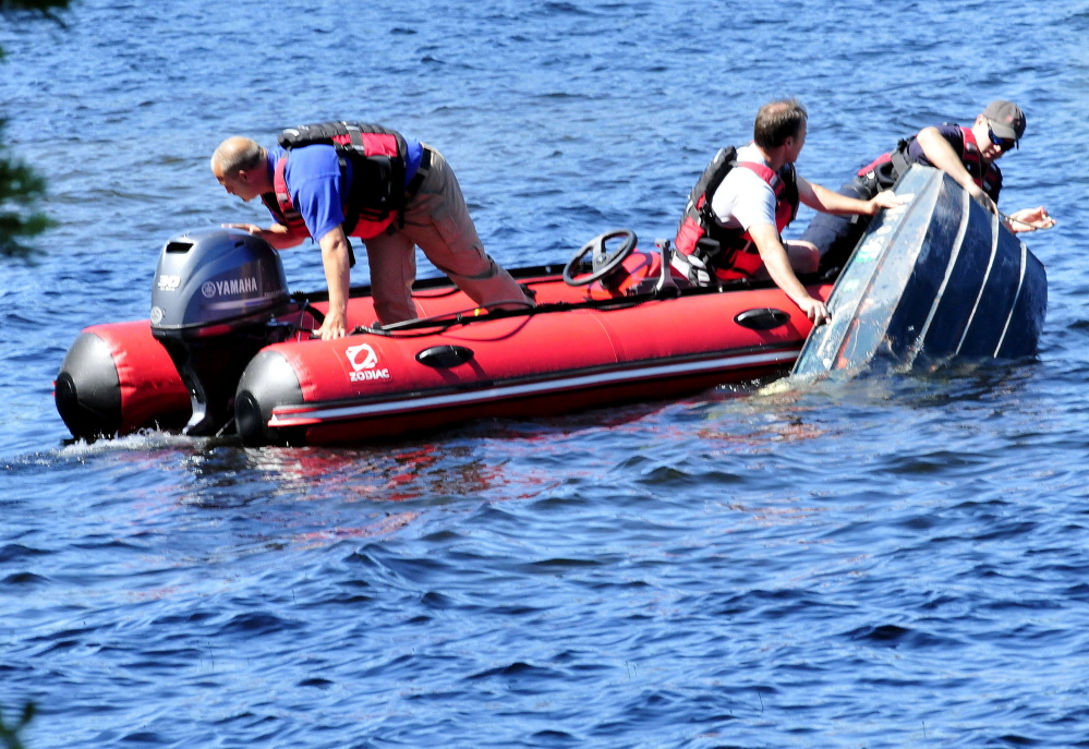 Skowhegan firefighters including Chief Shawn Howard, left, secure a sunken boat after it and fisherman Llewellyn Ryder, 66, of Clinton overturned in the choppy Lake George in Canaan on Wednesday. Ryder got out and made it to shore wet but unharmed.