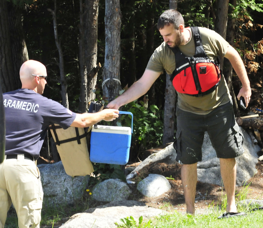 Lake George Regional Park Director Jeff McCabe, right, hands gear to a paramedic as boat operator Llewellyn Ryder was being checked inside an ambulance after he and boat overturned on Lake George in Canaan on Wednesday. McCabe jumped into the water to help Ryder get to shore.